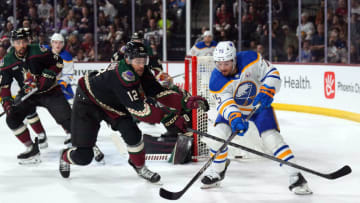 Dec 16, 2023; Tempe, Arizona, USA; Arizona Coyotes left wing Zach Sanford (12) checks Buffalo Sabres defenseman Connor Clifton (75) during the first period at Mullett Arena. Mandatory Credit: Joe Camporeale-USA TODAY Sports