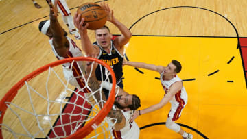 Jun 9, 2023; Miami, Florida, USA; Denver Nuggets center Nikola Jokic (15) shoots the ball against Miami Heat forward Jimmy Butler (left) and forward Caleb Martin (bottom) and center Cody Zeller (right) during the first half in game four of the 2023 NBA Finals at Kaseya Center. Mandatory Credit: Kyle Terada-USA TODAY Sports