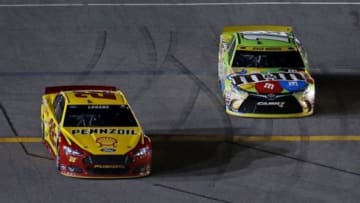 Nov 22, 2015; Homestead, FL, USA; Sprint Cup Series driver Joey Logano (22) beats Sprint Cup Series driver Kyle Busch (18) off of pit road during the Ford EcoBoost 400 at Homestead-Miami Speedway. Mandatory Credit: Peter Casey-USA TODAY Sports