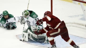 Apr 7, 2016; Tampa, FL, USA; North Dakota Fighting Hawks goalie Cam Johnson (33) makes a stop against Denver Pioneers forward Dylan Gambrell (7) as Hawks defenseman Tucker Poolman (3) slides by during the third period of the semifinals of the 2016 Frozen Four college ice hockey tournament at Amalie Arena. Mandatory Credit: Reinhold Matay-USA TODAY Sports