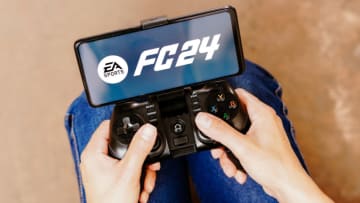 BRAZIL - 2023/08/08: In this photo illustration, a person playing on a joystick and the EA Sports FC 24 logo displayed on a smartphone screen. (Photo Illustration by Rafael Henrique/SOPA Images/LightRocket via Getty Images)
