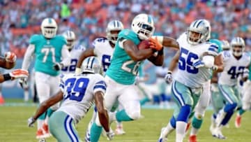 Aug 23, 2014; Miami Gardens, FL, USA; Miami Dolphins running back Knowshon Moreno (28) runs as Dallas Cowboys defensive end Martez Wilson (56) and cornerback Brandon Carr (39) defend in the first quarter of the game at Sun Life Stadium. Mandatory Credit: Brad Barr-USA TODAY Sports