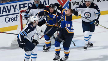 ST. LOUIS, MO - APRIL 16: Ivan Barbashev #49 of the St. Louis Blues gets hit by the stick of Jacob Trouba #8 of the Winnipeg Jets in Game Four of the Western Conference First Round during the 2019 NHL Stanley Cup Playoffs at Enterprise Center on April 16, 2019 in St. Louis, Missouri. (Photo by Joe Puetz/NHLI via Getty Images)