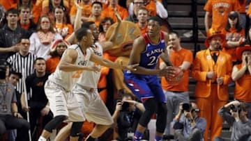 Mar 1, 2014; Stillwater, OK, USA; Kansas Jayhawks center Joel Embiid (21) is defended by Oklahoma State Cowboys forward/center Kamari Murphy (21) and guard Markel Brown (22) during the first half at Gallagher-Iba Arena. Mandatory Credit: Tim Heitman-USA TODAY Sports