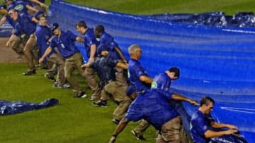 Aug 19, 2014; Chicago, IL, Grounds crew workers put the tarp down as rain delayed the Chicago Cubs game against the San Francisco Giants in the fifth inning at Wrigley Field. Mandatory Credit: Matt Marton-USA TODAY Sports