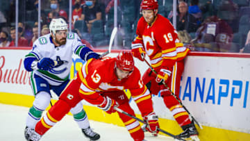 Oct 1, 2021; Calgary, Alberta, CAN; Calgary Flames left wing Johnny Gaudreau (13) and Vancouver Canucks right wing Conor Garland (8) battle for the puck during the third period at Scotiabank Saddledome. Mandatory Credit: Sergei Belski-USA TODAY Sports