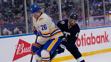 Mar 13, 2022; Hamilton, Ontario, CAN; Buffalo Sabres defenseman Rasmus Dahlin (26) defends against Toronto Maple Leafs forward Alexander Kerfoot (15) during the second period in the 2022 Heritage Classic ice hockey game at Tim Hortons Field. Mandatory Credit: John E. Sokolowski-USA TODAY Sports