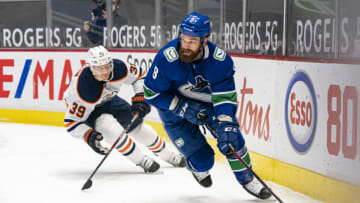 VANCOUVER, BC - MARCH 13: Jordie Benn #8 of the Vancouver Canucks tries to break free from Alex Chiasson #39 of the Edmonton Oilers during NHL action at Rogers Arena on March 13, 2021 in Vancouver, Canada. (Photo by Rich Lam/Getty Images)