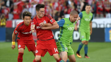 Jul 2, 2016; Toronto, Ontario, CAN; Seattle Sounders midfielder Osvaldo Alonso (6) battles for the ball with Toronto FC midfielder Jay Chapman (14) as forward Tsubasa Endoh (9) looks on in the first half at BMO Field. Mandatory Credit: Dan Hamilton-USA TODAY Sports