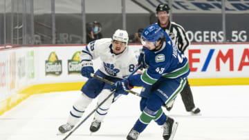 VANCOUVER, BC - APRIL 18: Quinn Hughes #43 of the Vancouver Canucks collects the loose puck while pressured by Nicholas Robertson #89 of the Toronto Maple Leafs during NHL hockey action at Rogers Arena on April 17, 2021 in Vancouver, Canada. (Photo by Rich Lam/Getty Images)