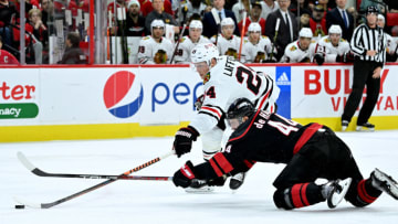 RALEIGH, NORTH CAROLINA - DECEMBER 27: Calvin de Haan #44 of the Carolina Hurricanes battles Sam Lafferty #24 of the Chicago Blackhawks for the puck during the second period of their game at PNC Arena on December 27, 2022 in Raleigh, North Carolina. (Photo by Grant Halverson/Getty Images)