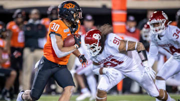 Nov 30, 2019; Stillwater, OK, USA; Oklahoma State Cowboys running back Chuba Hubbard (30) runs the ball against Oklahoma Sooners defensive lineman Dillon Faamatau (91) during the second half at Boone Pickens Stadium. Mandatory Credit: Rob Ferguson-USA TODAY Sports