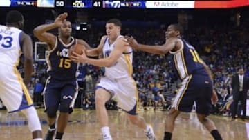 Apr 6, 2014; Oakland, CA, USA; Golden State Warriors guard Klay Thompson (11, center) drives to the basket against Utah Jazz center Derrick Favors (15) and guard Alec Burks (10) during the second quarter at Oracle Arena. Mandatory Credit: Kyle Terada-USA TODAY Sports
