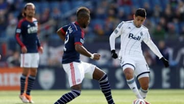 Mar 22, 2014; Foxborough, MA, USA; Vancouver Whitecaps midfielder Matias Laba (15) keeps the ball away from New England Revolution forward Dimitry Imbongo (92) during the second half at Gillette Stadium. The game ended in a 1-1 tie. Mandatory Credit: Greg M. Cooper-USA TODAY Sports