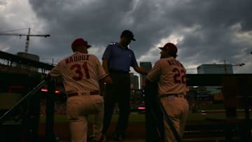 ST. LOUIS, MO - JULY 14: Mike Maddux #31 and Mike Matheny #22 of the St. Louis Cardinals discuss calling a rain delay in the first inning with umpire Jim Reynolds #77 during a game against the Cincinnati Reds at Busch Stadium on July 14, 2018 in St. Louis, Missouri. (Photo by Dilip Vishwanat/Getty Images)