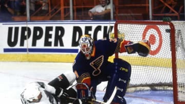 2000 Season: Curtis Joseph of the St. Louis Blues makes the save despite Tony Granato's aggressive effort. (Photo by Wen Roberts/Getty Images)