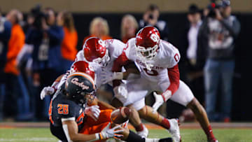 STILLWATER, OK - NOVEMBER 27: Wide receiver Blaine Green #28 of the Oklahoma State Cowboys loses the ball on a 15-yard catch after being downed by safety Patrick Fields #10, linebacker Shane Whitter #13, and cornerback Woodi Washington #0 of the Oklahoma Sooners at Boone Pickens Stadium on November 27, 2021 in Stillwater, Oklahoma. The Cowboys won 'Bedlam' 37-33. (Photo by Brian Bahr/Getty Images)
