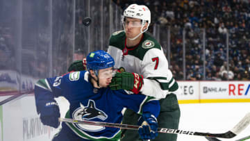 VANCOUVER, BC - OCTOBER 26: Quinn Hughes #43 of the Vancouver Canucks and Nico Sturm #7 of the Minnesota Wild battle for the loose puck along the boards during the first period of NHL action on October, 26, 2021 at Rogers Arena in Vancouver, British Columbia, Canada. (Photo by Rich Lam/Getty Images)