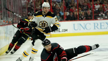 RALEIGH, NC - MAY 16: Nino Niederreiter #21 of the Carolina Hurricanes gets upended and attempts to control the puck on the ice as Brandon Carlo #25 of the Boston Bruins defends in Game Four of the Eastern Conference Third Round during the 2019 NHL Stanley Cup Playoffs on May 16, 2019 at PNC Arena in Raleigh, North Carolina. (Photo by Gregg Forwerck/NHLI via Getty Images)