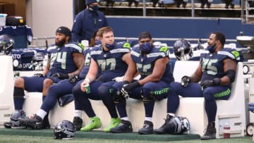 SEATTLE, WASHINGTON - DECEMBER 27: (L-R) Cedric Ogbuehi #74, Ethan Pocic #77, Jordan Simmons #66 and Duane Brown #76 of the Seattle Seahawks react from the sidelines in the second quarter against the Los Angeles Rams at Lumen Field on December 27, 2020 in Seattle, Washington. (Photo by Abbie Parr/Getty Images)