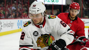 RALEIGH, NC - NOVEMBER 12: Chicago Blackhawks Center Luke Johnson (62) plays a puck along the boards in front of Carolina Hurricanes Center Sebastian Aho (20) during a game between the Chicago Blackhawks and the Carolina Hurricanes at the PNC Arena in Raleigh, NC on November 12, 2018. (Photo by Greg Thompson/Icon Sportswire via Getty Images)