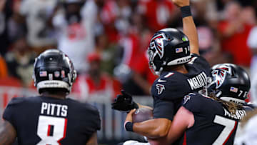 ATLANTA, GEORGIA - SEPTEMBER 11: Quarterback Marcus Mariota #1 of the Atlanta Falcons is lifted by offensive tackle Kaleb McGary #76 of the Atlanta Falcons after Mariota's rushing touchdown during the fourth quarter against the New Orleans Saints at Mercedes-Benz Stadium on September 11, 2022 in Atlanta, Georgia. (Photo by Todd Kirkland/Getty Images)