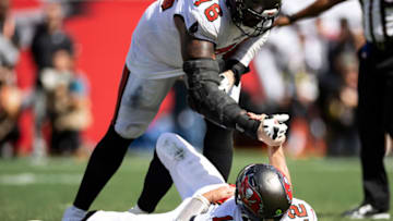 Oct 9, 2022; Tampa, Florida, USA; Tampa Bay Buccaneers quarterback Tom Brady (12) gets help off the ground during the second half against the Atlanta Falcons at Raymond James Stadium. Mandatory Credit: Matt Pendleton-USA TODAY Sports