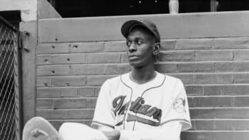 Portrait of American baseball player Satchel Paige (born Leroy Robert Paige, 1906 - 1982) of the Cleveland Indians as he sits on the ground next to the dugout and watches his team practice, Cleveland, Ohio, July 1948. (Photo by George Silk/The LIFE Picture Collection/Getty Images)