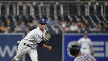 SAN DIEGO, CA - AUGUST 30: Luis Urias #9 of the San Diego Padres throws over Matt Holliday #7 of the Colorado Rockies but didn't get the double play at first base in the sixth inning of a baseball game at PETCO Park on August 30, 2018 in San Diego, California. Trevor Story scored on the play. (Photo by Denis Poroy/Getty Images)