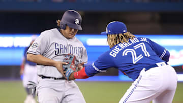 TORONTO, ON - MAY 25: Josh Naylor #22 of the San Diego Padres is tagge dout as he tries to advance to third base by Vladimir Guerrero Jr. #27 of the Toronto Blue Jays in the first inning during MLB game action at Rogers Centre on May 25, 2019 in Toronto, Canada. (Photo by Tom Szczerbowski/Getty Images)