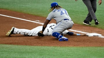 ST PETERSBURG, FLORIDA - JULY 24: Manuel Margot #13 of the Tampa Bay Rays slides safely under the glove of Vladimir Guerrero Jr. #27 of the Toronto Blue Jays on a throw over from Rafael Dolis #41 (not pictured) during the eighth inning on Opening Day at Tropicana Field on July 24, 2020 in St Petersburg, Florida. The 2020 season had been postponed since March due to the COVID-19 pandemic. (Photo by Douglas P. DeFelice/Getty Images)