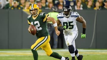 Sep 20, 2015; Green Bay, WI, USA; Green Bay Packers quarterback Aaron Rodgers (12) scrambles away from Seattle Seahawks defensive end Demarcus Dobbs (95) in the second quarter at Lambeau Field. Mandatory Credit: Benny Sieu-USA TODAY Sports