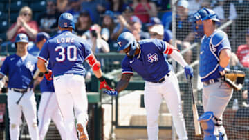 SURPRISE, ARIZONA - MARCH 31: Adolis Garcia #53 of the Texas Rangers high fives Nathaniel Lowe #30 after Lowe hit a home run against the Los Angeles Dodgers during the third inning of the MLB spring training game at Surprise Stadium on March 31, 2022 in Surprise, Arizona. (Photo by Christian Petersen/Getty Images)
