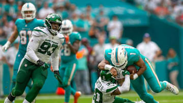 Miami Dolphins quarterback Tua Tagovailoa (1), runs over New York Jets cornerback Michael Carter II (30) during second half action against the New York Jets during NFL game at Hard Rock Stadium Sunday in Miami Gardens.
