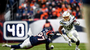 DENVER, CO - DECEMBER 1: Austin Ekeler #30 of the Los Angeles Chargers carries the ball and evades a tackle attempt by Jeremiah Attaochu #97 of the Denver Broncos in the fourth quarter of a game at Empower Field at Mile High on December 1, 2019 in Denver, Colorado. (Photo by Dustin Bradford/Getty Images)
