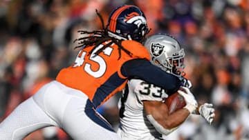 DENVER, CO - DECEMBER 29: DeAndre Washington #33 of the Oakland Raiders is hit by Alexander Johnson #45 of the Denver Broncos in the second quarter of a game at Empower Field at Mile High on December 29, 2019 in Denver, Colorado. (Photo by Dustin Bradford/Getty Images)