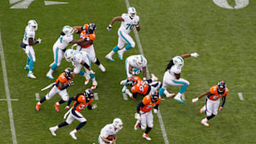 DENVER, CO - NOVEMBER 23: Quarterback Ryan Tannehill #17 of the Miami Dolphins carries the ball against the Denver Broncos defense at Sports Authority Field at Mile High on November 23, 2014 in Denver, Colorado. The Broncos defeated the Dolphins 39-36. (Photo by Doug Pensinger/Getty Images)
