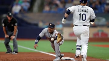 ST. PETERSBURG, FL - MARCH 29: Yuli Gurriel #10 of the Houston Astros reaches for a throw that pulled him off the base and lead to Mike Zunino #10 of the Tampa Bay Rays being safe at first base in the third inning of a baseball game at Tropicana Field on March 29, 2019 in St. Petersburg, Florida. (Photo by Mike Carlson/Getty Images)