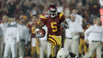 PASADENA, CA - JANUARY 04: Running back Reggie Bush #5 of the USC Trojans carries the football past Aaron Harris #2 of the Texas Longhorns before fumbling the ball on the play in the second quarter during the BCS National Championship Rose Bowl Game on January 4, 2006 in Pasadena, California. (Photo by Donald Miralle/Getty Images)