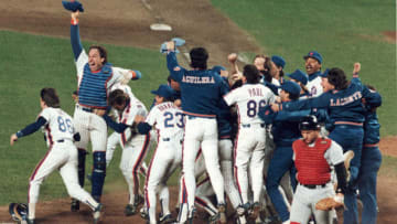 Members of the New York Mets baseball team celebrate their victory in game six of the World Series at Shea Stadium, Flushing, New York, October 25, 1986. They went on to defeat the Boston Red Sox in the series four games to three. Visible players include Mets catcher Gary Carter (at left with arm raised), and teammates Wally Backman (who hugs Carter), coach Bud Harrelson (#23), and Rick Aguilera; Red Sox catcher Rich Gedman (at right, in red uniform) walks way dejectedly. (Photo by Robert Riger/Getty Images)