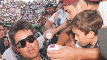 Vinny Castilla of the Colorado Rockies tries to escape a crush of fans and autograph seekers prior to a game against the San Diego Padres at Monterrey Stadium in Monterrey, Mexico 04 April 1999. Castilla is from Mexico. (Photo by PAUL BUCK / AFP) (Photo by PAUL BUCK/AFP via Getty Images)