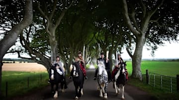 ANTRIM, NORTHERN IRELAND - AUGUST 29: Four actors on horseback dressed in Game of Thrones related costumes carry the Queen's Baton as they make their way way along the Dark Hedges on August 29, 2017 in Antrim, Northern Ireland. The Dark Hedges near Stranocum in County Antrim featured as the King's Road in season two of Game of Thrones and has become a tourist mecca for fans of the television series along with other filming locations in the province. The Queen's Baton Relay is currently on a tour of the United Kingdom as it makes its way around Europe in preparation for the 2018 Commonwealth Games in Australia. (Photo by Charles McQuillan/Getty Images)