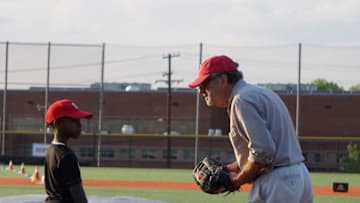 A coach speaks with a boy as he practices baseball skills at the Nationals Youth Baseball Academy in Washington, DC, on May 7, 2018. - On a searing hot summer's day in Washington, a group of children are playing baseball in a pristine park that stands at odds with its surroundings in the city's rough-and-tumble southeast.Parents and grandparents shout encouragement from the stands as they chow down on hot dogs, some seeking shelter under the shade of a blue tent. This quintessential scene is taking place in little leagues across the United States -- and would be unremarkable if it weren't for the stark color divide in the stands: one section is entirely white and the other all black, reflected in the players on the field.Currently batting are an African American youth team of 12-year-olds representing the Mamie Johnson league of southeast DC. (Photo by Issam AHMED / AFP) (Photo credit should read ISSAM AHMED/AFP via Getty Images)