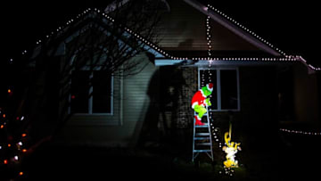 A cutout of The Grinch and his sidekick Max is seen on a ladder holding a line of string lights from the rooftop of a house, Monday, Dec. 21, 2020, along Rita Lyn Court on the east side of Iowa City, Iowa.201221 Holiday Lights 005 Jpg