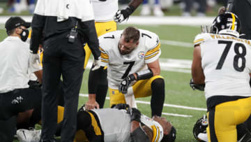 Ben Roethlisberger #7 of the Pittsburgh Steelers checks on injured teammate Zach Banner (Photo by Jim McIsaac/Getty Images)