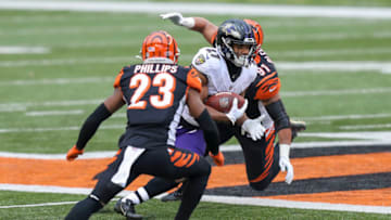Jan 3, 2021; Cincinnati, Ohio, USA; Baltimore Ravens running back J.K. Dobbins (27) runs with the ball past Cincinnati Bengals cornerback Darius Phillips (23) and defensive end Amani Bledsoe (91) in the first half at Paul Brown Stadium. Mandatory Credit: Katie Stratman-USA TODAY Sports