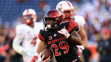 SAN DIEGO, CA - NOVEMBER 24: Rashaad Penny #20 of the San Diego State Aztecs eludes Bijon Parker #4 and DaQuan Baker #37 of the New Mexico Lobos for a rushing touchdown during the second half of a game at Qualcomm Stadium on November 24, 2017 in San Diego, California. (Photo by Sean M. Haffey/Getty Images)