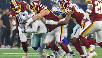 ARLINGTON, TEXAS - NOVEMBER 22: Ezekiel Elliott #21 of the Dallas Cowboys fights for yards against Mason Foster #54, Matthew Ioannidis #98, and Josh Harvey-Clemons #40 of the Washington Redskins at AT&T Stadium on November 22, 2018 in Arlington, Texas. (Photo by Richard Rodriguez/Getty Images)