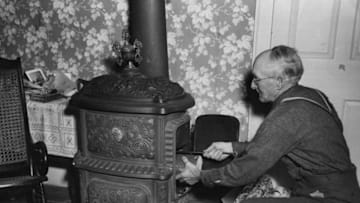 circa 1950: An elderly American gentleman getting his old fashioned 'shunck' stove burning. (Photo by Three Lions/Getty Images)