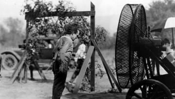 circa 1925: Harold Lloyd (1893 - 1971), the American film comedian puts a wind machine to good use to blow himself clean after rolling in the dust during a film sequence. (Photo by Hulton Archive/Getty Images)